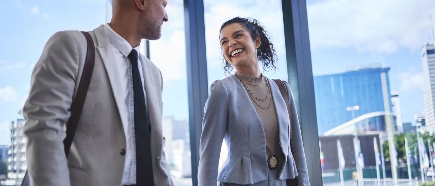 Zwei Geschäftsreisende im Gespräch auf dem Weg durch ein modernes Gebäude