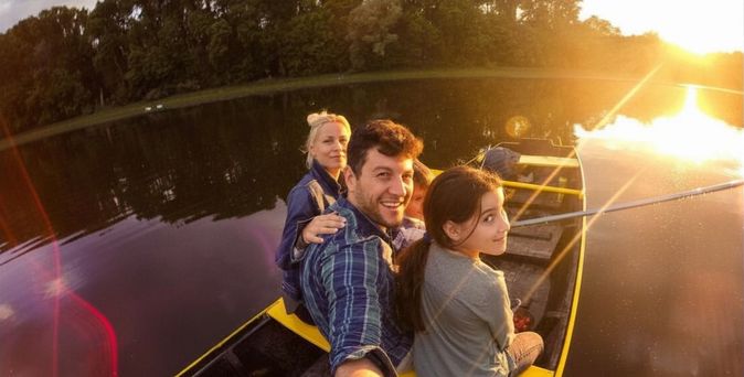 Familie sitzt bei Sonnenuntergang in einem Boot auf einem ruhigen See
