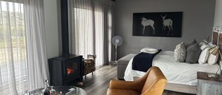 Modernes Gästezimmer mit Doppelbett, Ledersesseln, Kaminofen und Schwarz-Weiß-Wandbild.