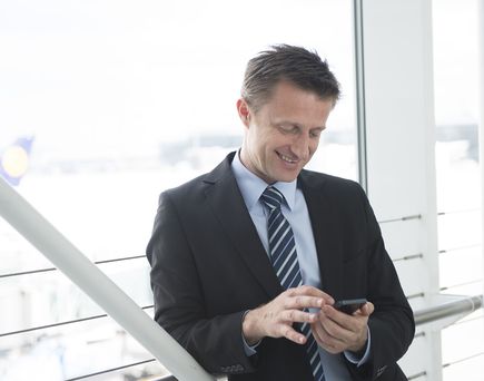Mann mit Handy am Flughafen