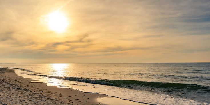 Sonnenuntergang am Ostseestrand bei Prerow mit sanften Wellen, goldenem Licht und feinem Sandstrand im Vordergrund.