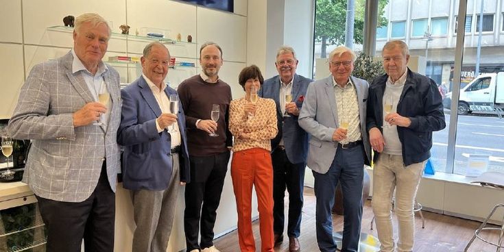 Gruppe von sieben Personen stößt mit Sektgläsern im Lufthansa City Center Niederrhein an – Symbol für Teamgeist und Unternehmensjubiläum.