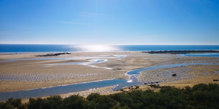 Blick über die sandige Küsten- und Lagunenlandschaft bei Cacela Velha an der Algarve mit kleinen Wasserläufen und Atlantik im Hintergrund.