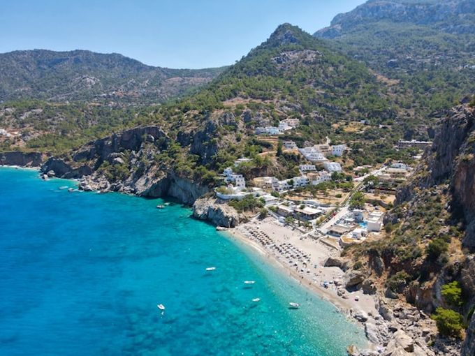 Drohnenansicht auf ein kleines Dorf direkt am Strand auf Karpathos
