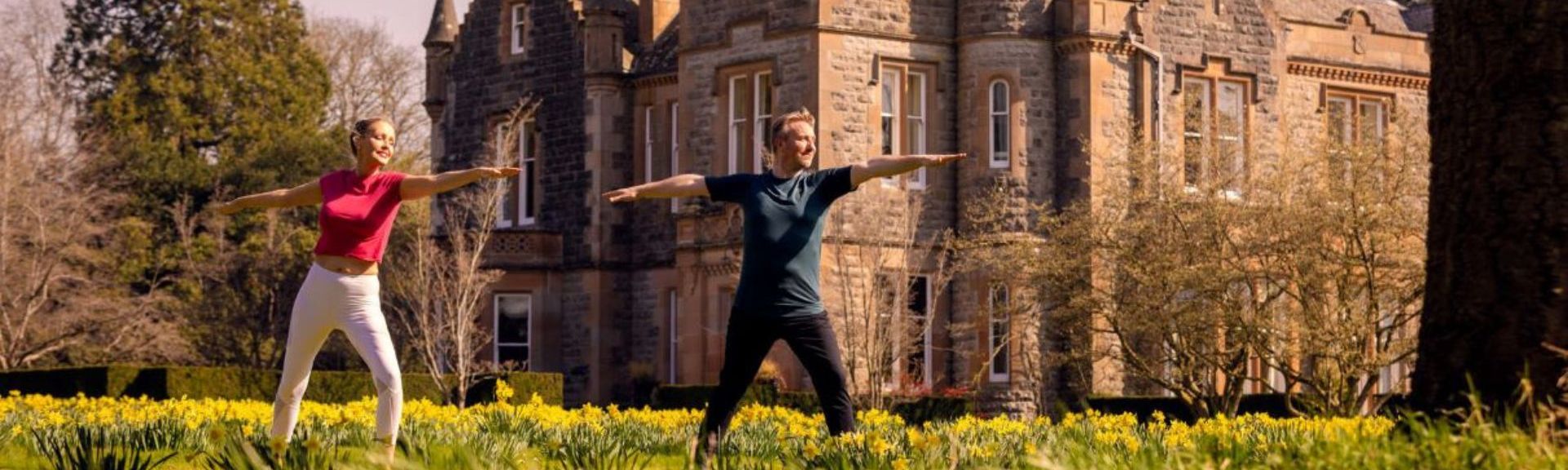 Zwei Personen tanzen oder bewegen sich fröhlich vor einem historischen Gebäude in Irland.