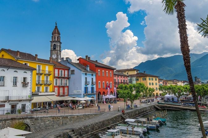 Seepromenade in Ascon mit bunten Häusern, See und Kirche San Pietro e Paolo