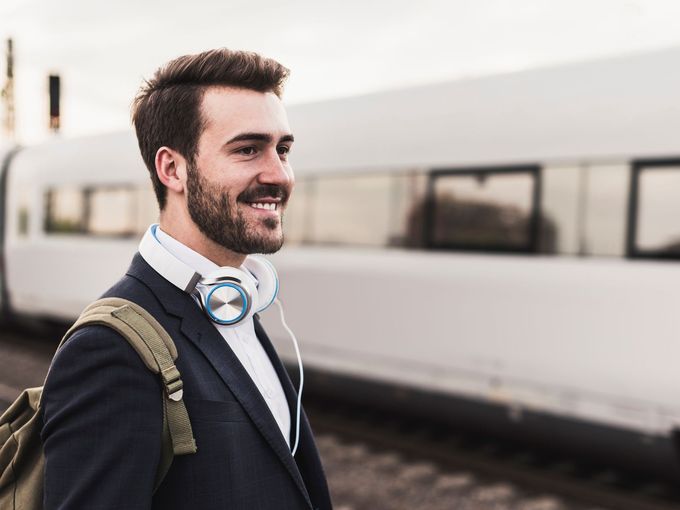Junger Mann am Bahnsteig während ein Zug vorbeifährt