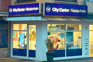 Außenansicht eines Reisebüros im City Center mit Schaufenster, Reiseangeboten und Eingangsbereich.