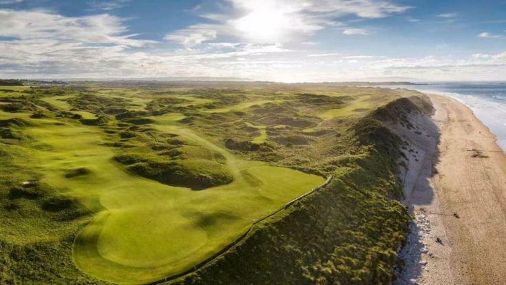 Luftaufnahme einer grünen irischen Küstenlandschaft mit Wanderwegen und Klippen.