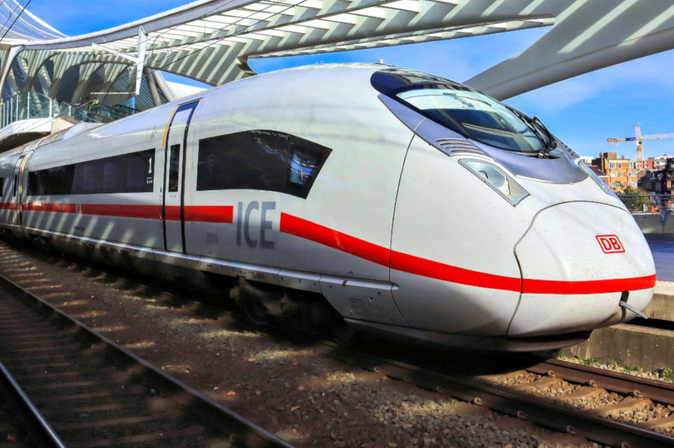 Weißer ICE 3neo-Zug der Deutschen Bahn mit rotem Streifen steht am Bahnhof unter einer modernen, geschwungenen Dachkonstruktion.
