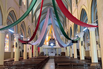 Blick in eine Kirche mit bunten Stoffbannern, die von der Decke hängen
