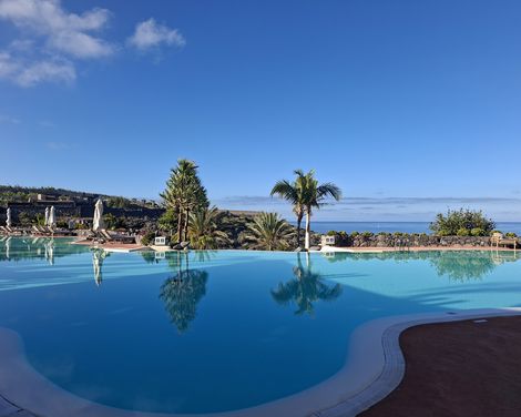Weitläufiger Außenpool des Ritz-Carlton mit Palmen, Sonnenliegen und Blick auf den Atlantik.