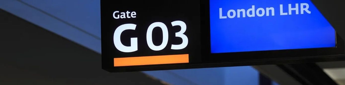 Reisende am Gate im Flughafen London Heathrow mit Handgepäck