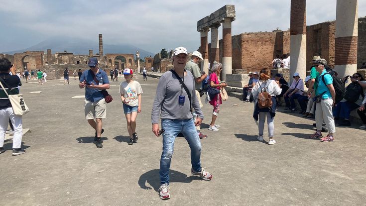 Touristengruppe erkundet die antiken Ruinen von Pompeji unter blauem Himmel.