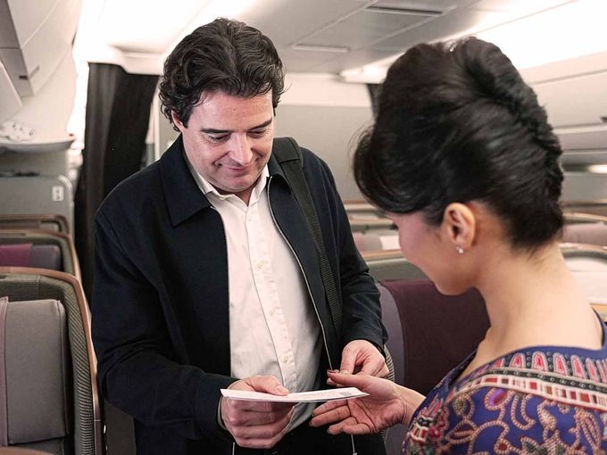 Flugbegleiterin reicht einem Passagier an Bord ein Dokument.