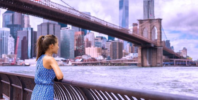 Touristin in New York schaut auf Brooklyn Bridge und Skyline