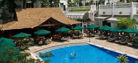 Weißes Hotel mit Bäumen im Vordergrund und leichter Beleuchtung 