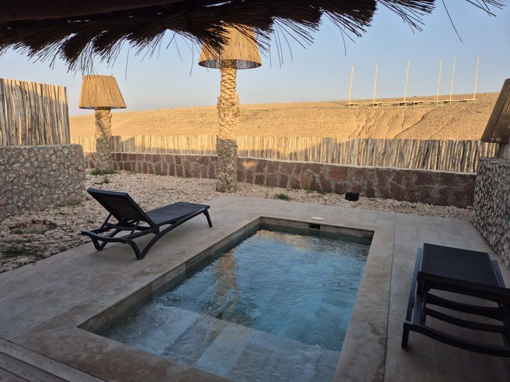 Hotelzimmer mit eigenem Swimmingpool und Liege und Ausblick auf die Wüste