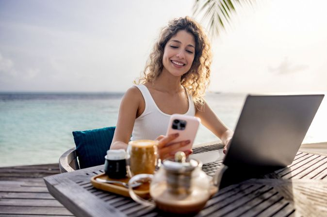 Geschäftsreisende mit Laptop nah am Strand © GettyImages