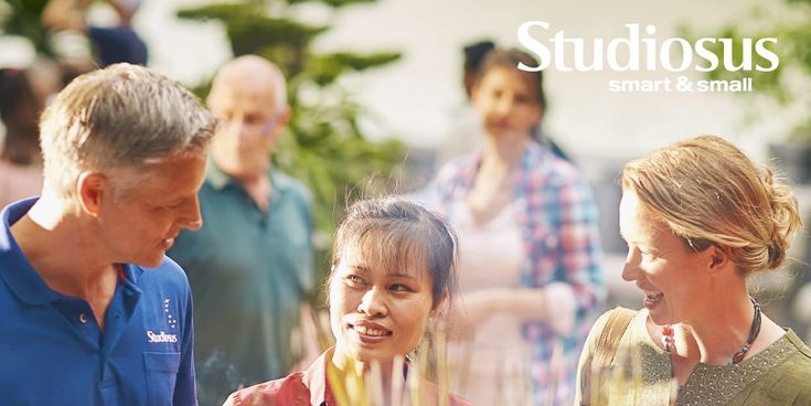 Mehrere Personen unterhalten sich freundlich vor einer großen Schale mit brennenden Räucherstäbchen. Im Hintergrund stehen weitere Menschen in einer ruhigen, grünen Umgebung. Rechts oben im Bild ist das Logo „Studiosus smart & small“ sichtbar.