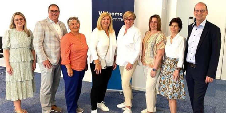 Gruppenfoto von acht Personen vor einem Lufthansa City Center Banner – Symbol für Austausch und Zusammenarbeit im Franchise-Netzwerk.