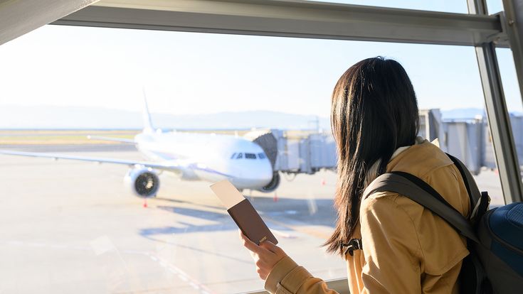 Frau mit Reisepass vor Flugzeug