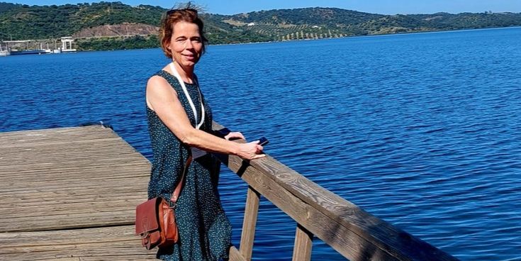 Monika Heuer steht auf einem Holzsteg und blickt aufs Wasser