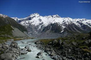 Steine am Fluss vor schneebedecktem Berg in Neuseeland