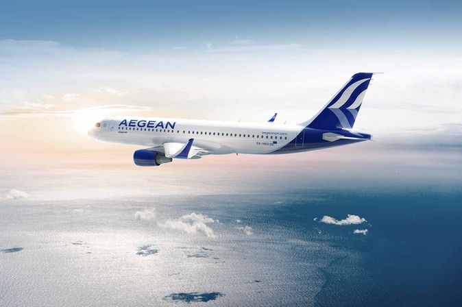 Ein Aegean Airlines Flugzeug fliegt über dem Meer bei Sonnenlicht durch den klaren Himmel.