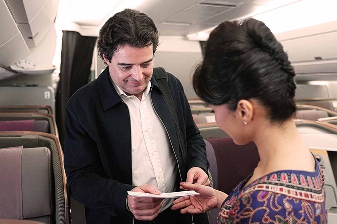 Flugbegleiterin reicht einem Passagier an Bord ein Dokument.