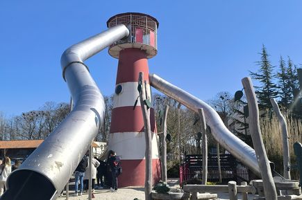 Spielplatz mit einer Rutsche, die aus einem Leuchtturm startet