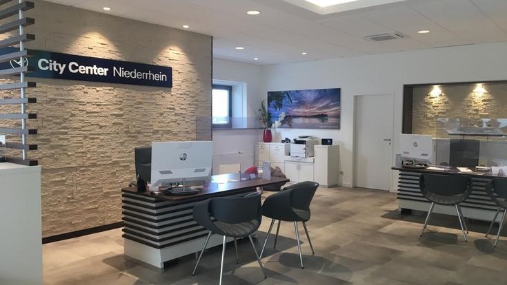 Innenansicht des Reisebüros City Center Niederrhein mit modernem Design, Arbeitsplätzen und Steinwand mit Firmenlogo.