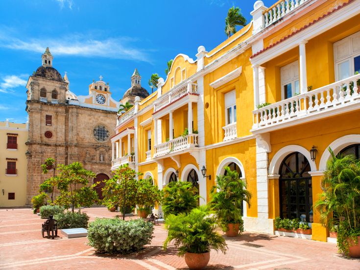 Gelbes Kolonialhaus mit Pflanzenkübeln und weißen Balkonen