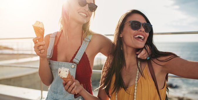 Zwei Frauen mit Sonnenbrillen genießen Eis am Meer