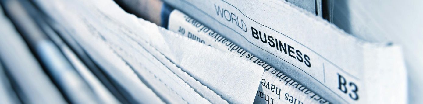 Nahaufnahme eines Stapels von Zeitungen mit sichtbarem Abschnitt der Wirtschaftsseite, auf dem ‚World Business‘ steht.