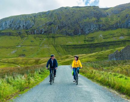 Zwei Radfahrer genießen eine Tour durch die hügelige, grüne Natur Irlands.