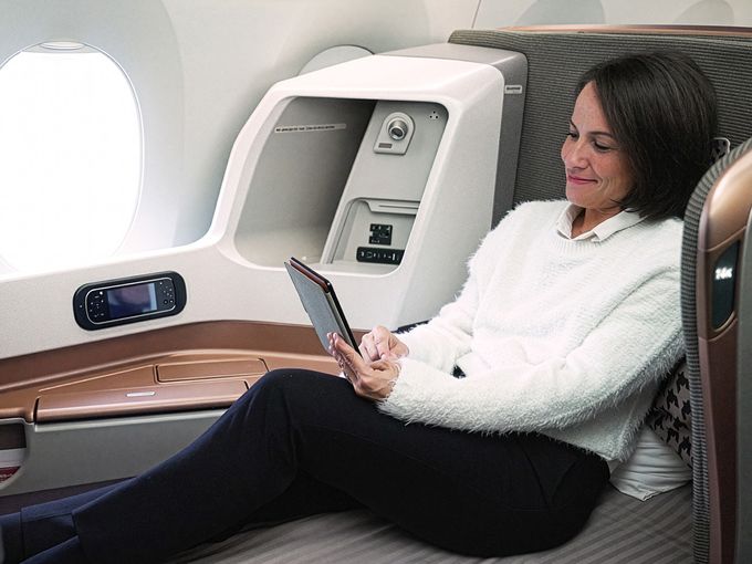 Frau entspannt sich mit einem Tablet in der Business Class einer Singapore Airlines Maschine.