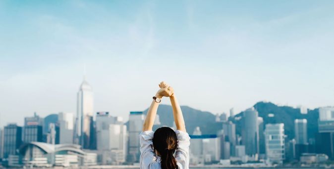 Frau streckt sich vor der Kulisse Hongkongs