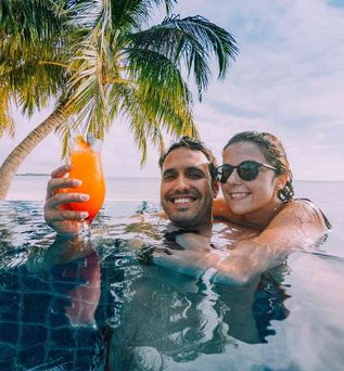 Paar im Pool mit Cocktail