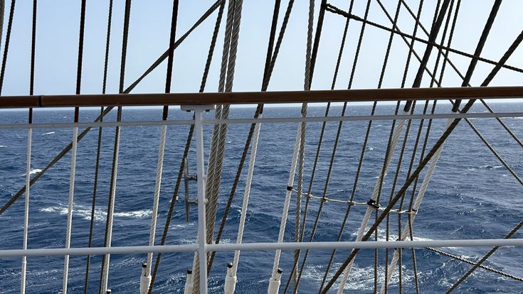 Segel und Seile eines Bootes mit Blick auf das tiefblaue Mittelmeer.