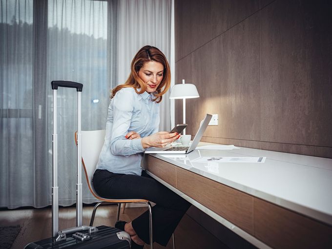 Geschäftsreisende nutzt Laptop und Smartphone im Hotelzimmer