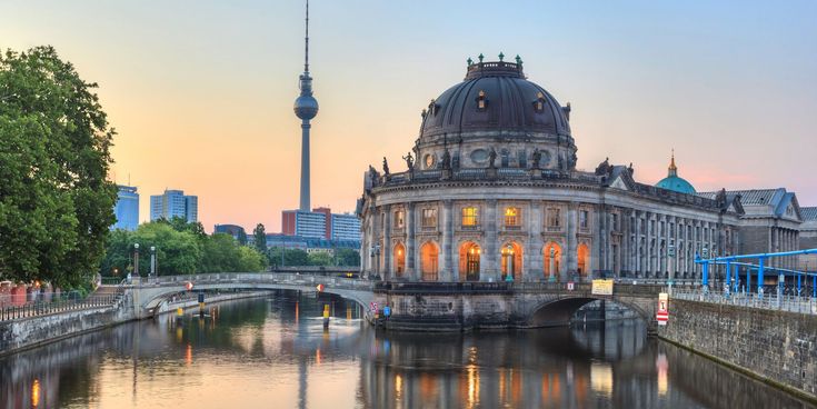 Blick auf den Berliner Dom und die Spree bei Sonnenuntergang mit dem Fernsehturm im Hintergrund.
