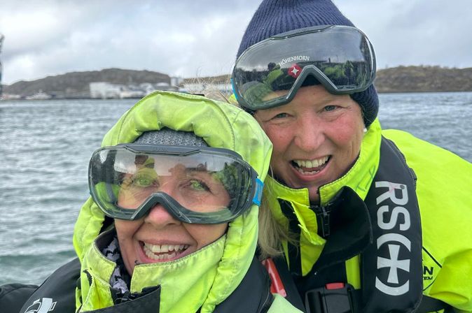 Sandra Janissen auf einem Ausflugs- oder Tenderboot vor schneebedeckten Bergen.