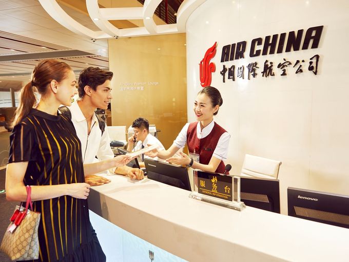 Zwei Passagiere werden freundlich an der Rezeption der Air China Lounge begrüßt.