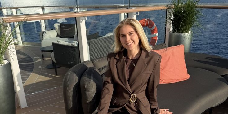 Marie Castor sitzt lächelnd in einem braunen Hosenanzug auf einer Sonnenliege an Deck der Silver Ray, das Meer im Hintergrund.