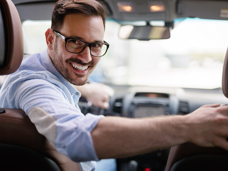 Mann im Auto blickt in Rückscheibe