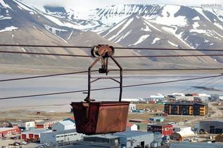 Blick auf braune Industriegondel vor Meer und Bergen