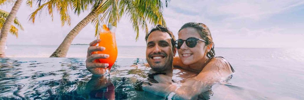 Paar im Pool mit Cocktail