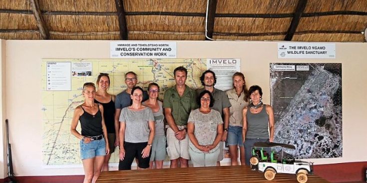 Gruppe von Personen in Safari-Kleidung steht vor Infotafeln zu Community- und Naturschutzprojekten von Imvelo – Symbol für nachhaltigen Tourismus in Afrika.