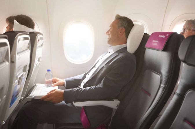 businessman lying back in his seat on board of an Eurowings flight